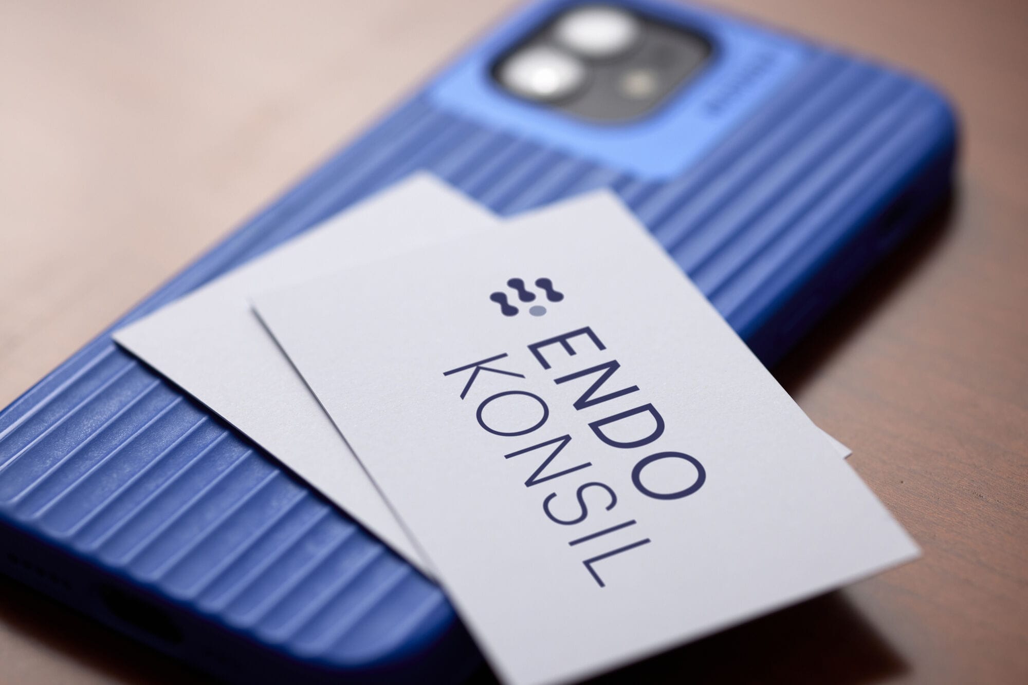 Ein blaues Smartphone mit EndoKonsil Visitenkarten.